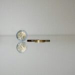 a gold ring with a coin on top of it