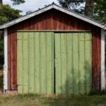 a red and green shed sitting in the middle of a field