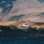 white red and chapel on grass field near mountain